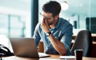 Mann am PC hält sich gestresst an den Kopf
