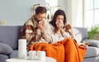 Ein junges Paar schnäuzt sich zu Hause ins Taschentuch.