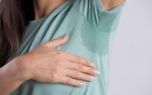 Großer Schweißfleck unter der Achsel einer Frau in grünem Shirt.