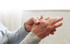 Ältere Person hält sich schmerzende Hand – Symbol für rheumatische Beschwerden