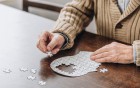 Ältere Person legt ein Puzzle in Form eines Kopfes