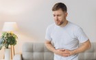 Mann mit Magenschmerzen im Wohnzimmer