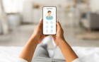 Eine Person hält ein Smartphone in den Händen, auf dessen Bildschirm eine medizinische Service-App mit einem Arzt-Symbol zu sehen ist.